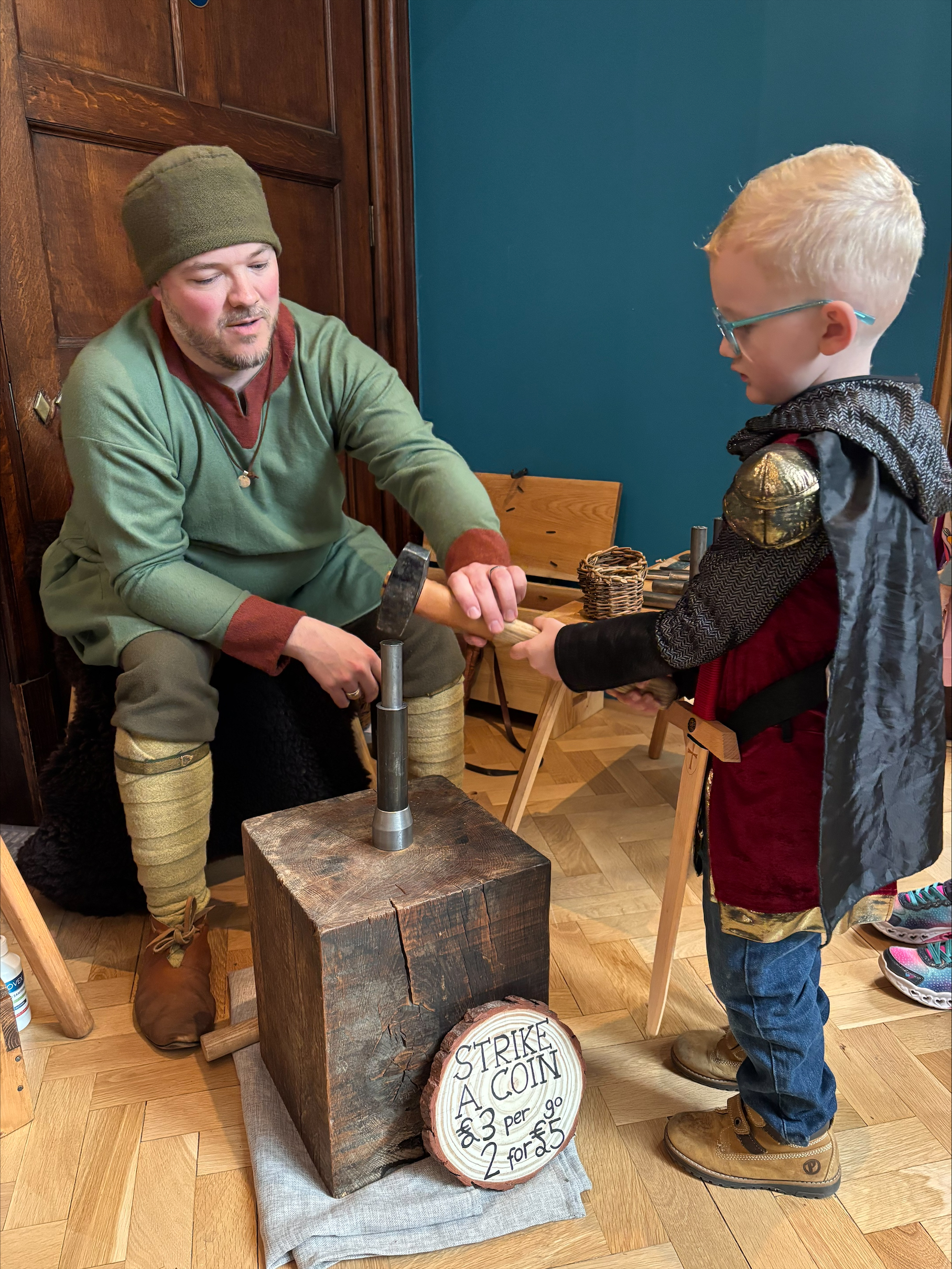 Child holding a hammer and striking a coin at Rochester Guildhall Museum