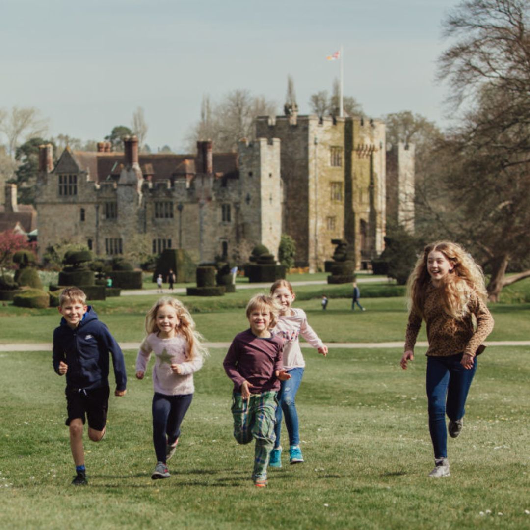 Five children running on grass with Hever Castle in the background